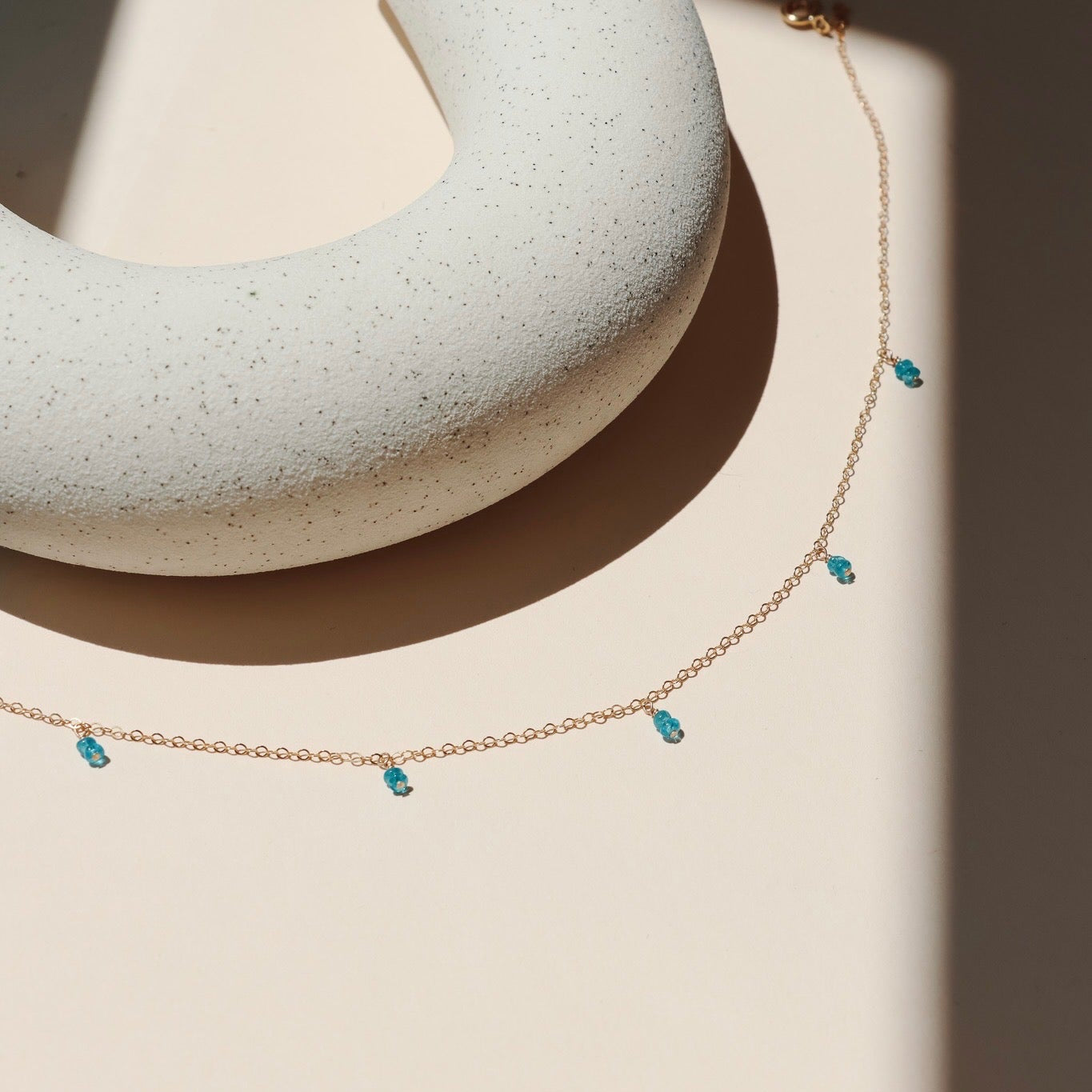 14k gold fill delicate chain necklace with gemstone charms in the sunlight