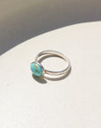 Sterling silver canyon ring with turquoise stone resting on a stoneware dish.