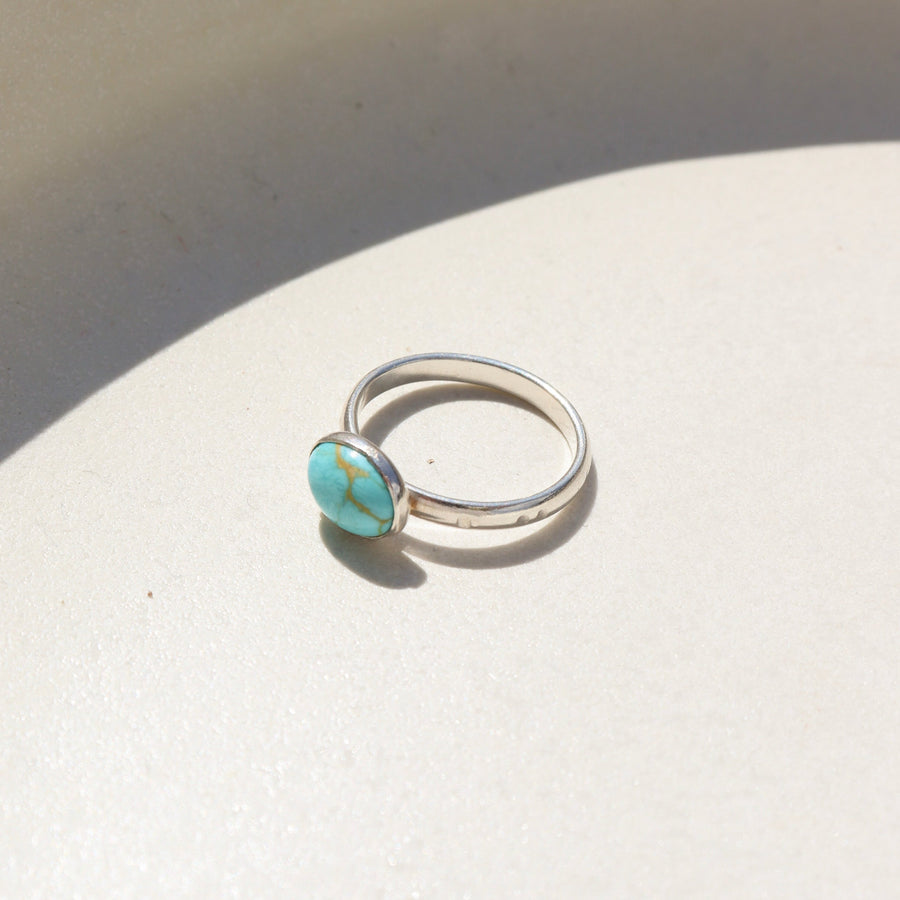 Sterling silver canyon ring with turquoise stone resting on a stoneware dish.