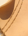 14k gold fill Callie chain laid on a tan plate