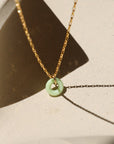 Chrysoprase donut shaped gemstone pendant attached to a 14k gold Fill chain in the sunlight