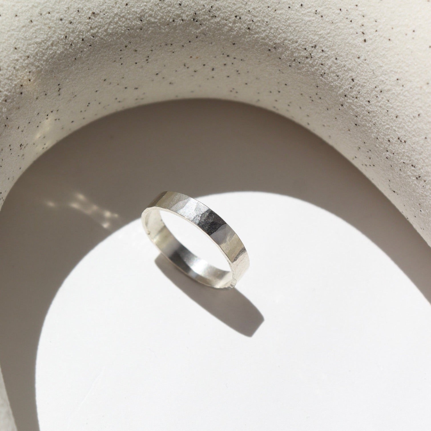 sterling silver hammered band ring on a light surface