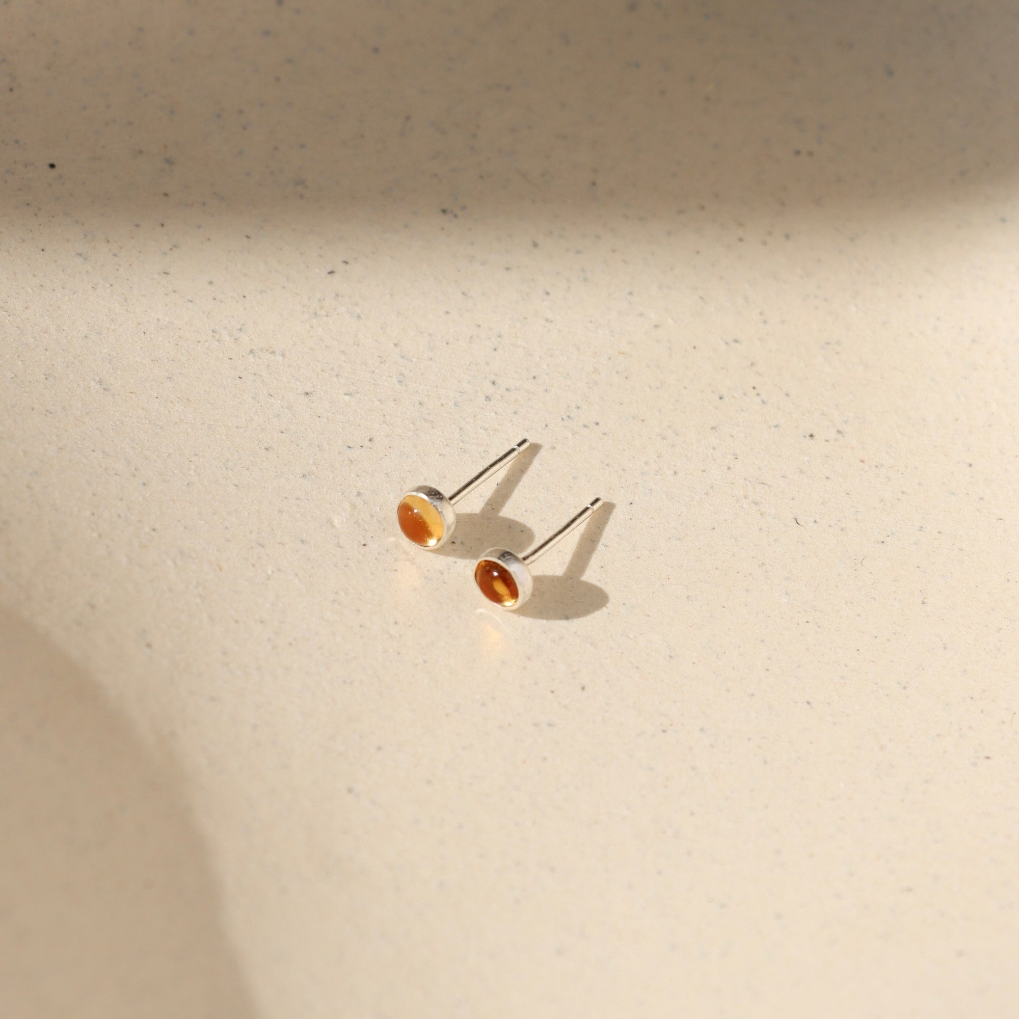sterling silver bezel ear posts with 4mm citrine stone on a light background