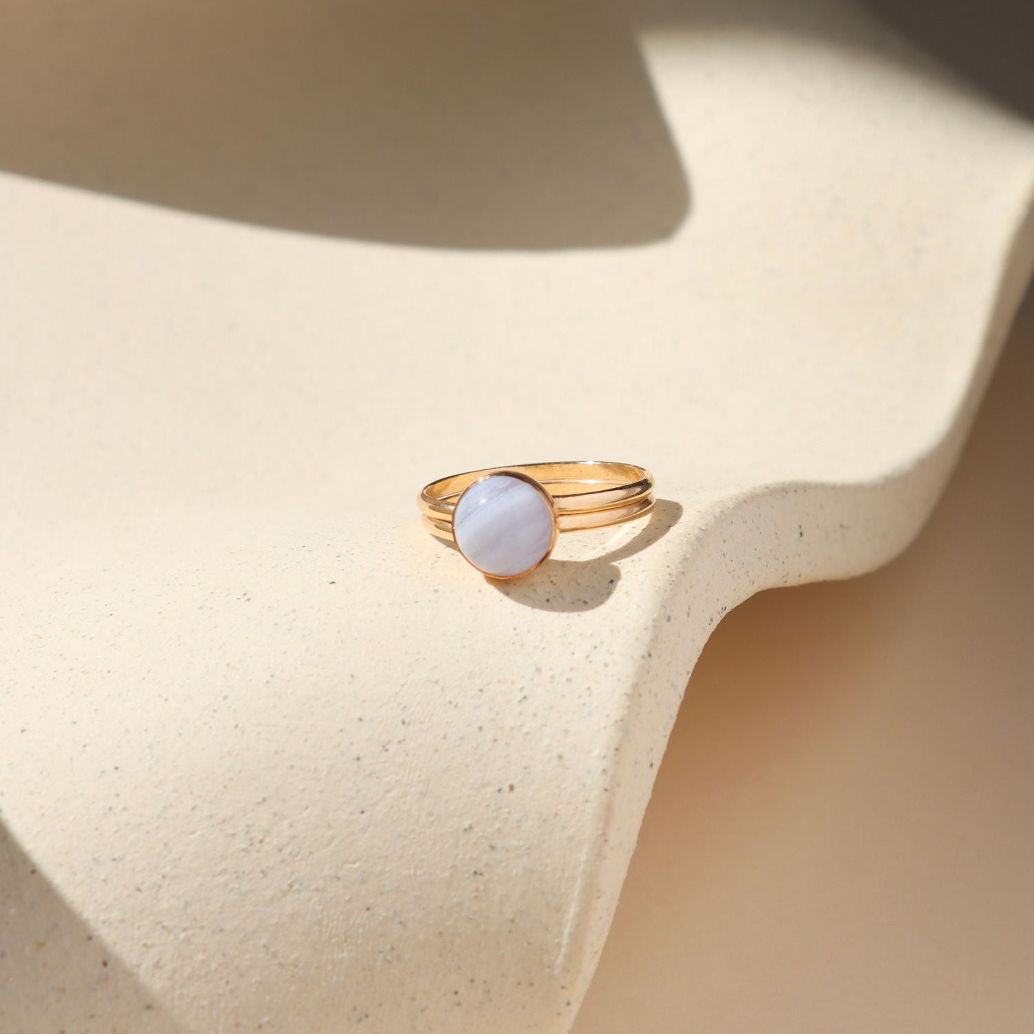 14k gold fill double band bezel ring with round blue lace agate stone on a light dish