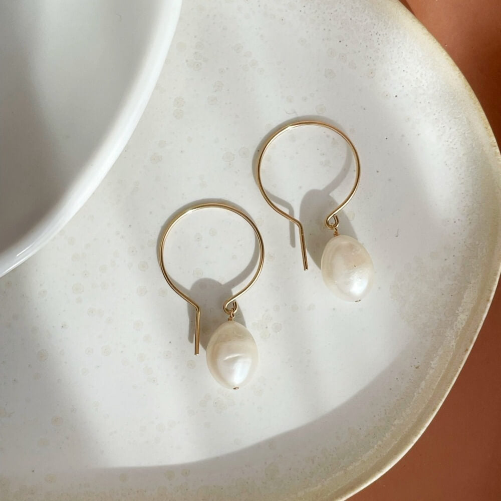 14k gold fill shaped earrings with fresh water pearls on a light dish