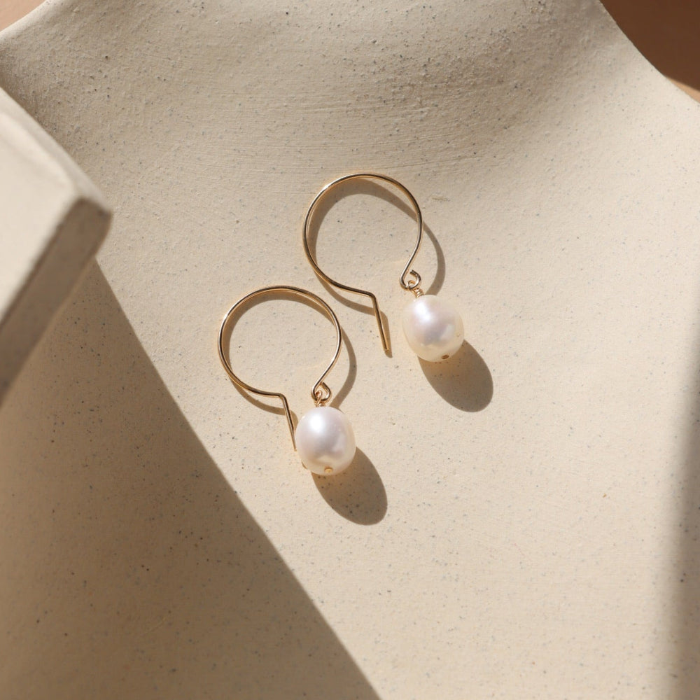 14k gold fill shaped earrings with fresh water pearls on a light dish