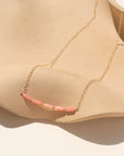 14k gold-filled necklace with five coral tube gemstones and serpentine beads, displayed on a tan dish.​