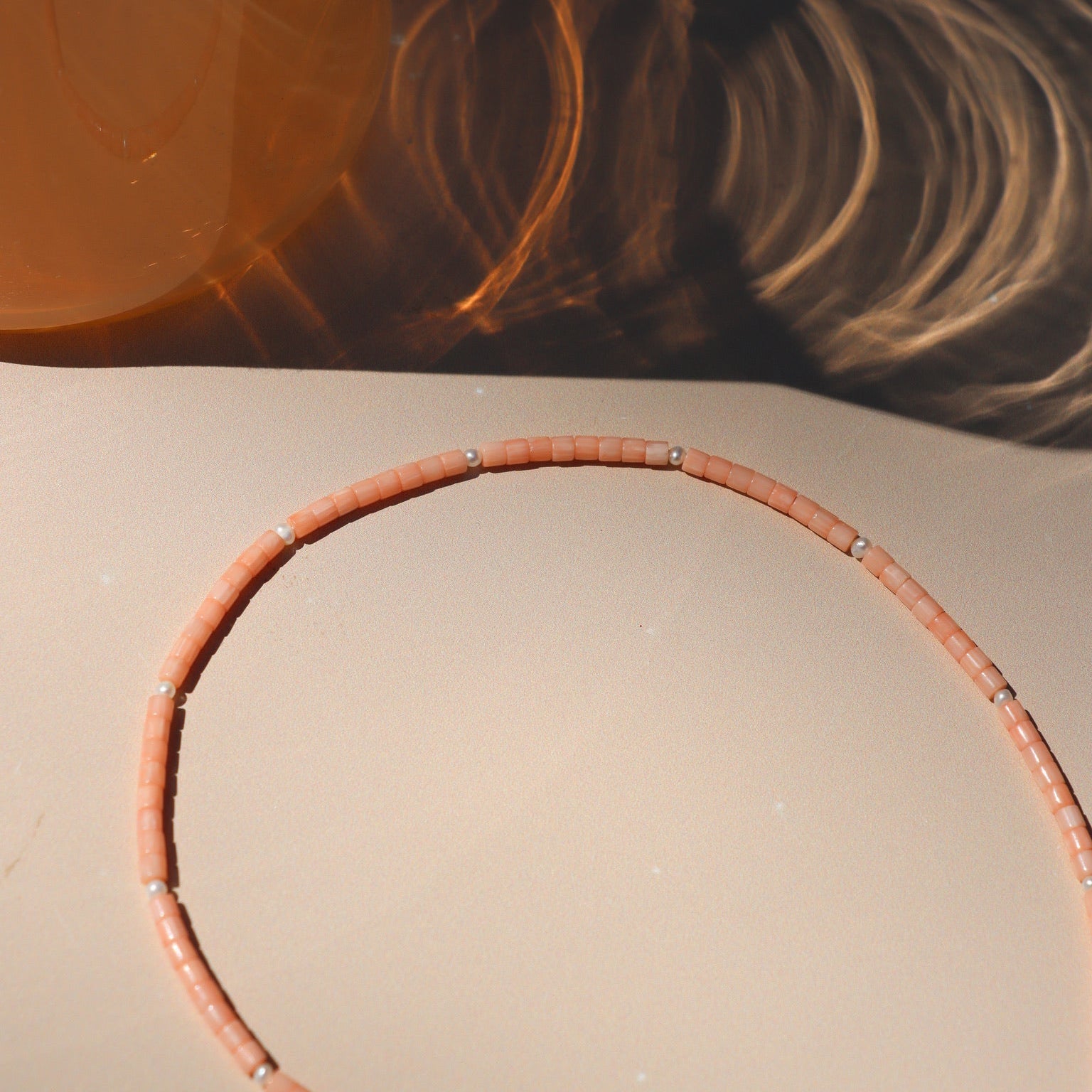 coral and pearl beaded necklace on a light surface