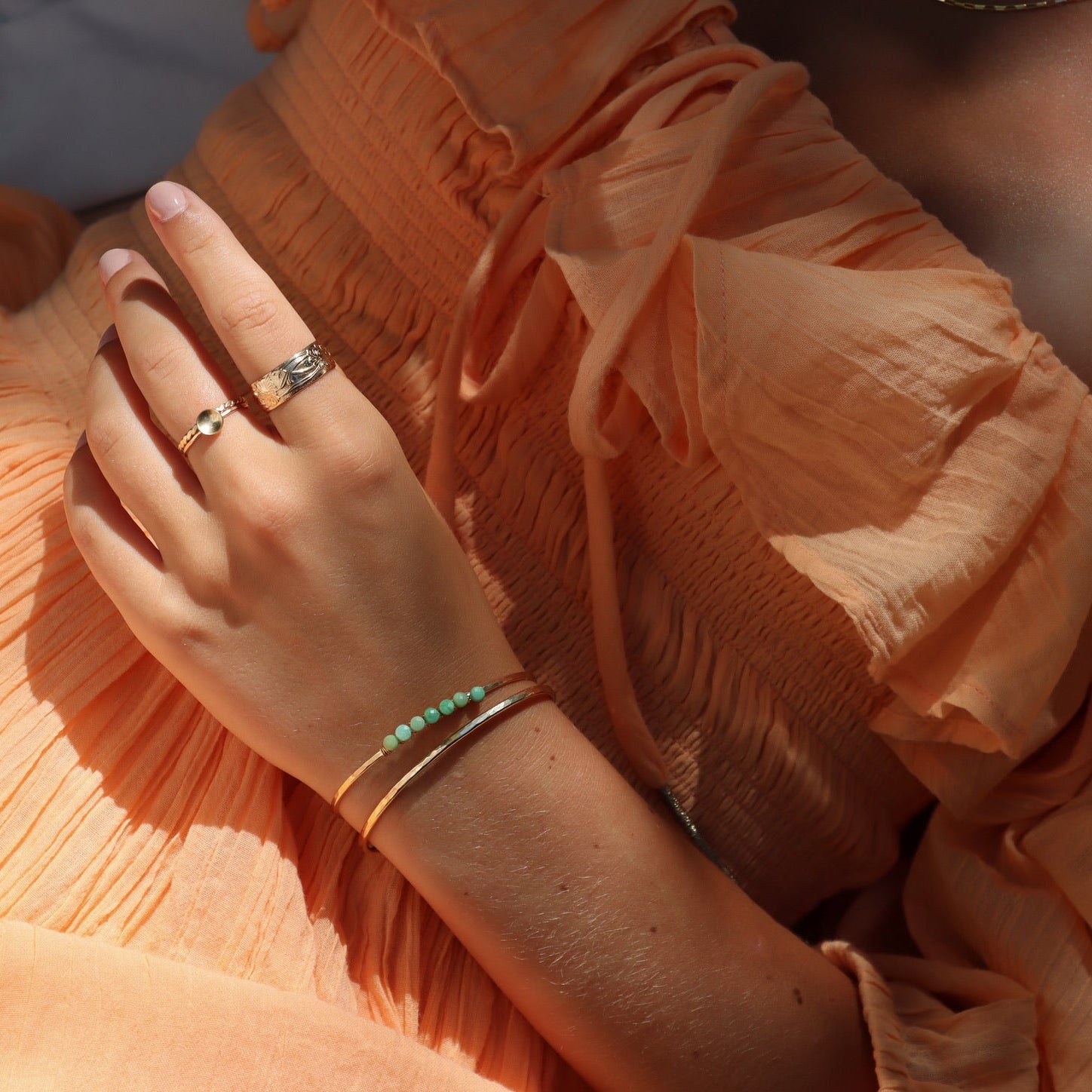 model wearing sterling silver delicate band ring with curved disc paired with other sterling silver jewelry