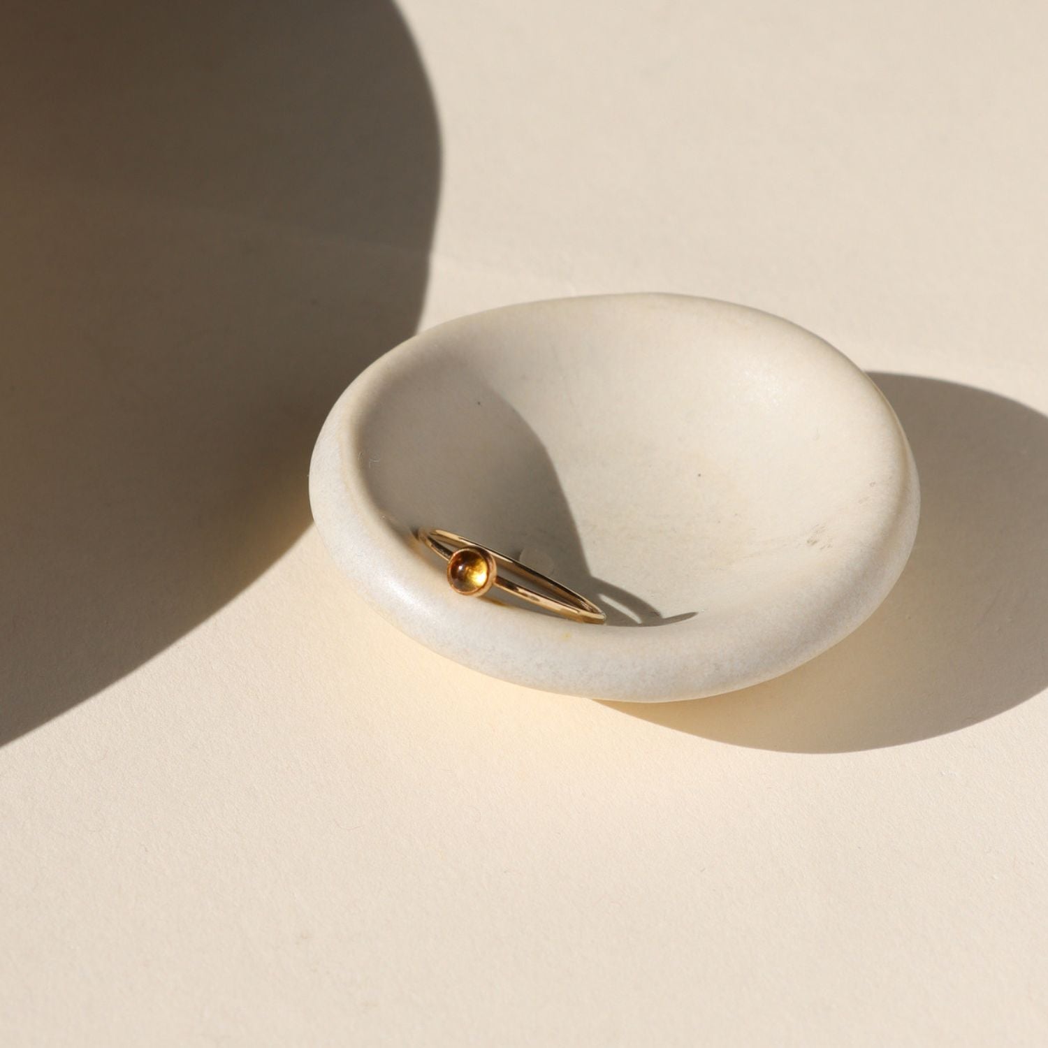 14k gold fill ring with round citrine stone on a light bowl