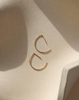 14k gold fill half circle shaped threader earrings on a light dish