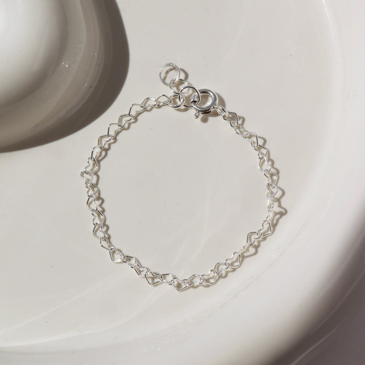 925 sterling silver heart link chain in children&#39;s sizes, photographed on a ceramic white plate