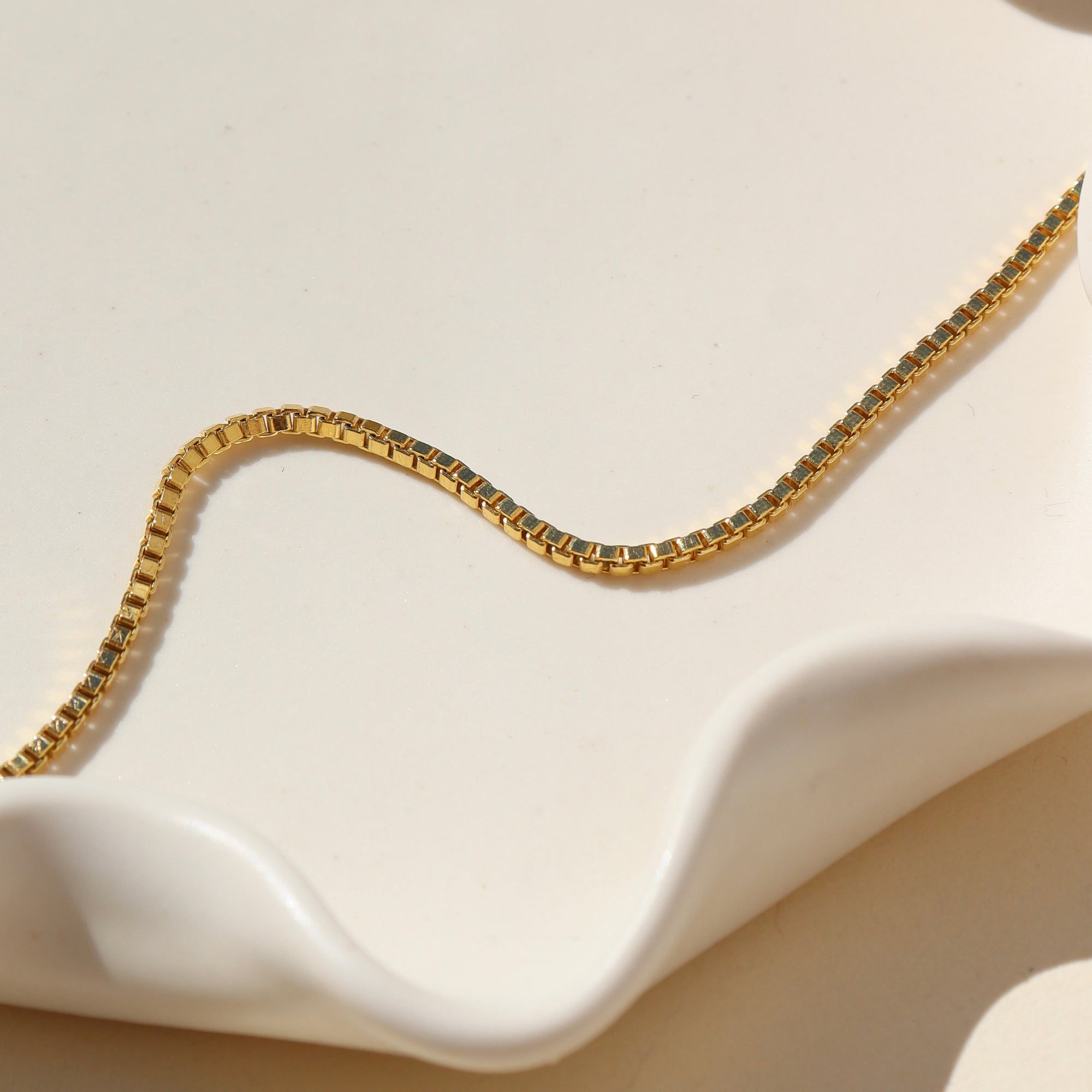 14k Gold Fill Curb Chain on a beige jewelry dish in natural lighting 