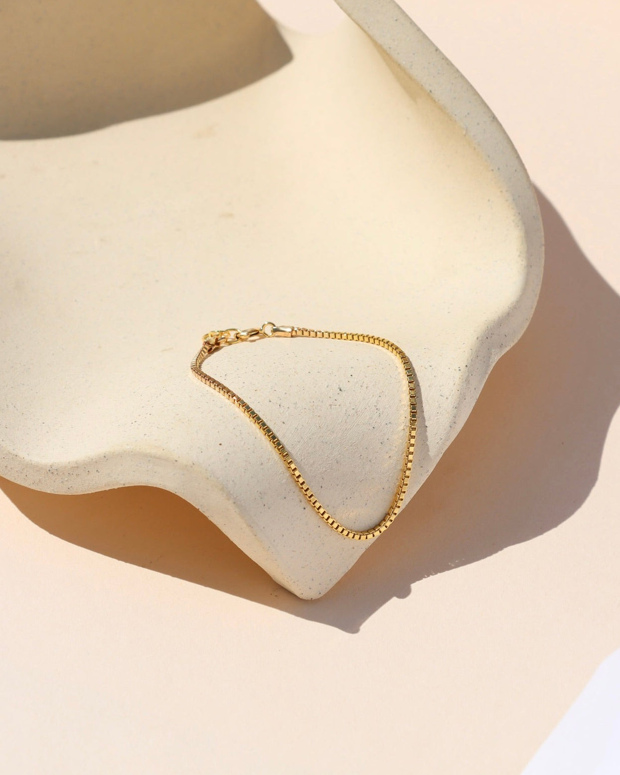 gold fill box chain bracelet on a wavy dish