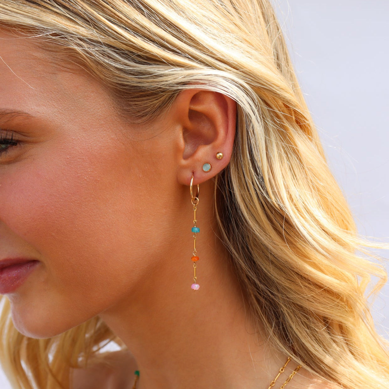 Model wearing 14k gold filled drop earrings with colorful opals in between links.