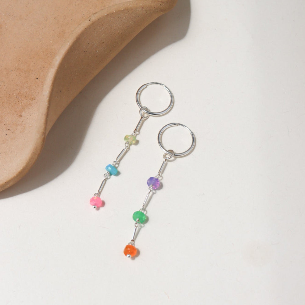 Disco Opal Earrings featuring six multicolored opals on a bar, dot, and dash chain design in sterling silver, dangling from a minimal hoop 