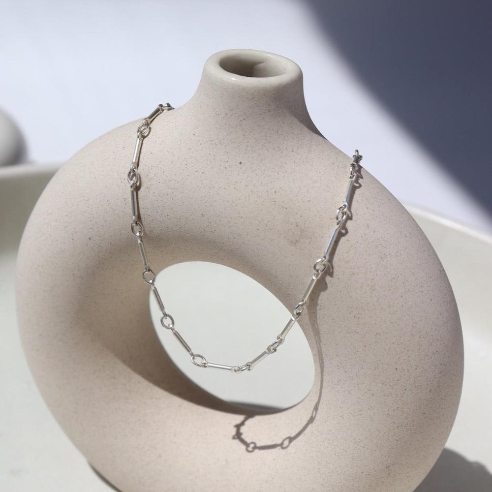 sterling silver bar and link chain anklet on a light vase