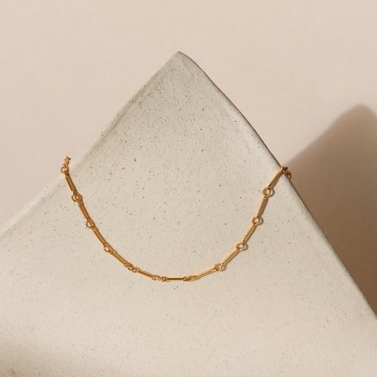 14k gold fill bar and link chain necklace on a light dish