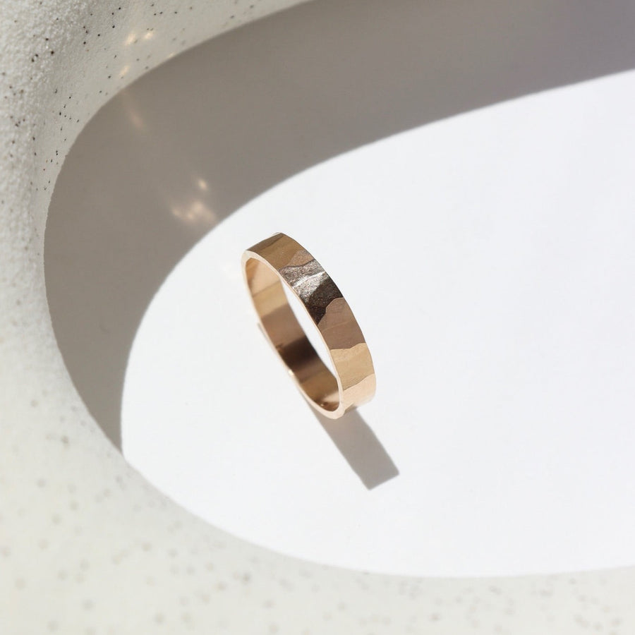14k gold fill cigar style ring laid on a white plate in the sunlight. This ring features a hammered band