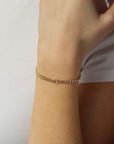 Model wearing a half and half 14k gold fill bracelet featuring a thick curb chain and a double vine chain. Also known as our Demi Alexandra and Makara chains.