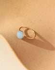 A 14k gold fill hammered gold band with a 8mm aquamarine gemstone set in a gold bezel. The ring is displayed on a orange dish. 