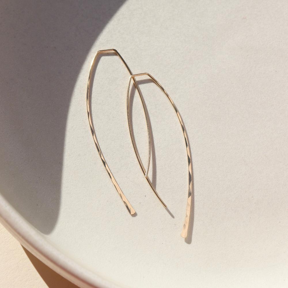 14k gold fill hammered shaped earrings on a light dish