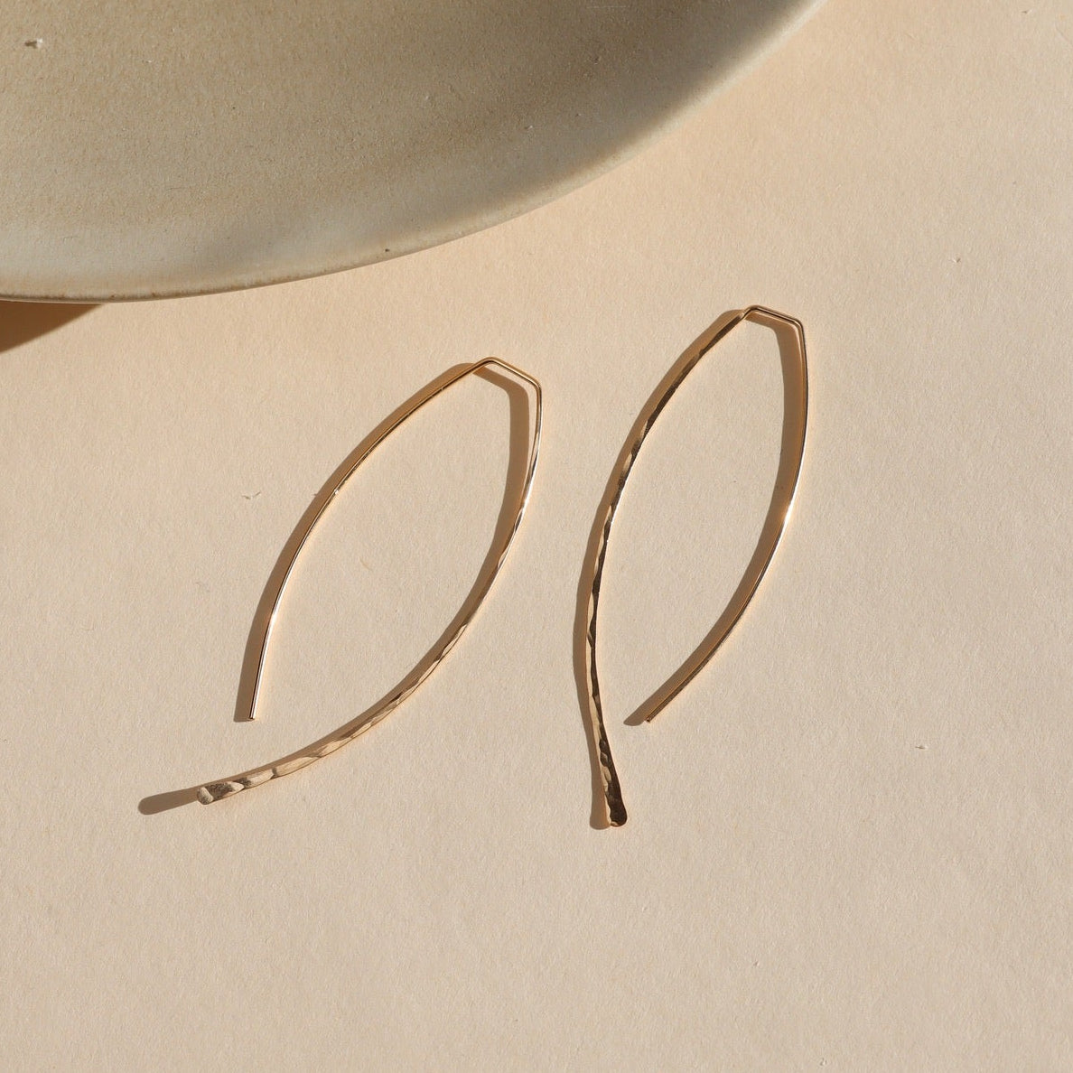 14k gold fill hammered shaped earrings on a light dish