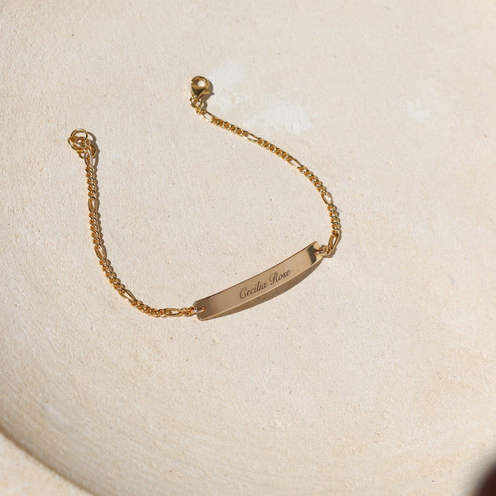 14k gold fill chain and bar bracelet with custom engraving on bar on a light dish