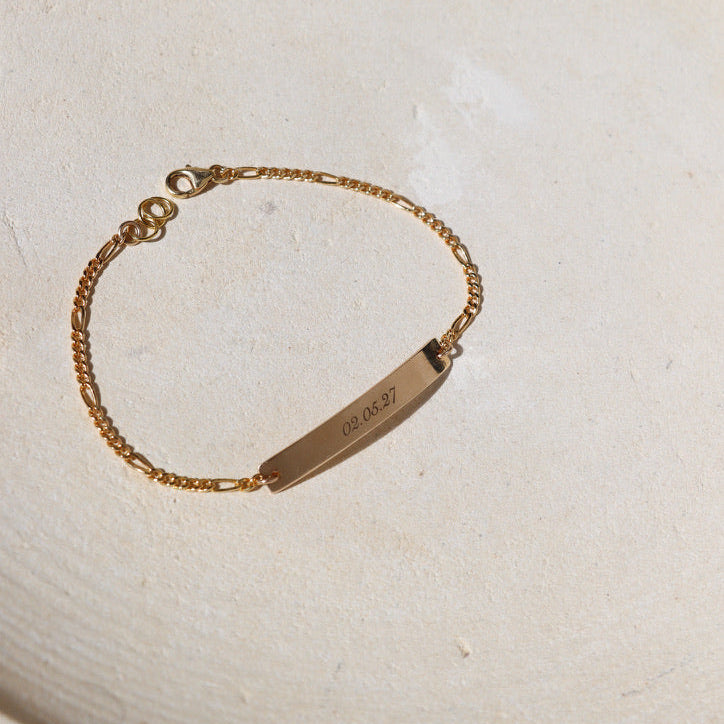 14k gold fill chain and bar bracelet with custom engraving on bar on a light dish