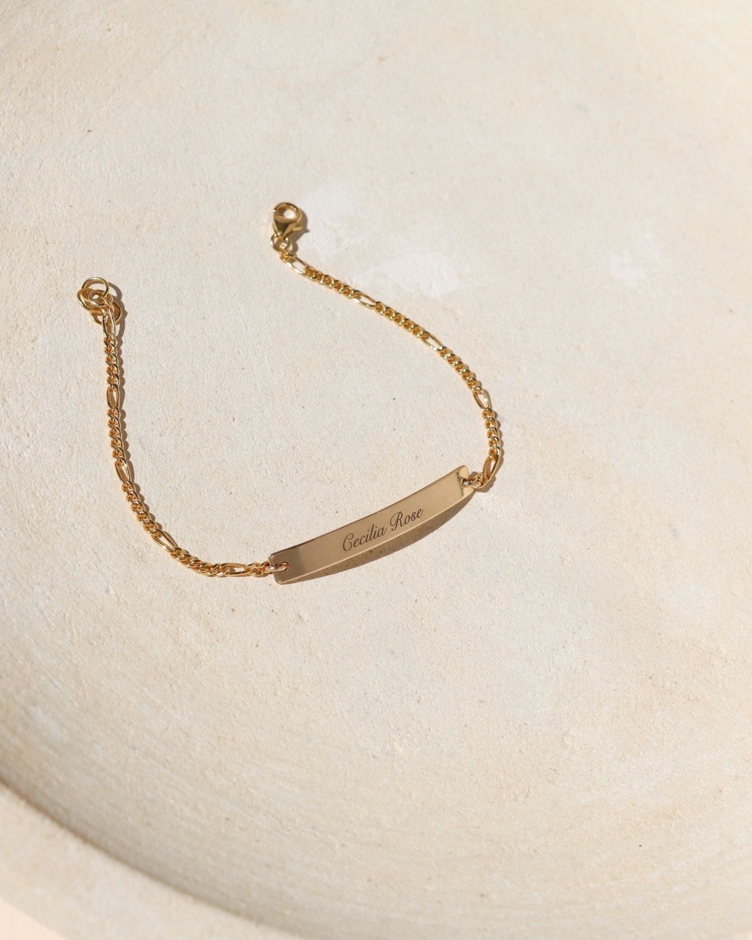 14k gold fill engraved bar and chain bracelet on a light dish