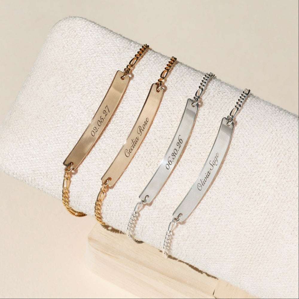 Set of gold and silver bracelets with engraved text on a white surface
