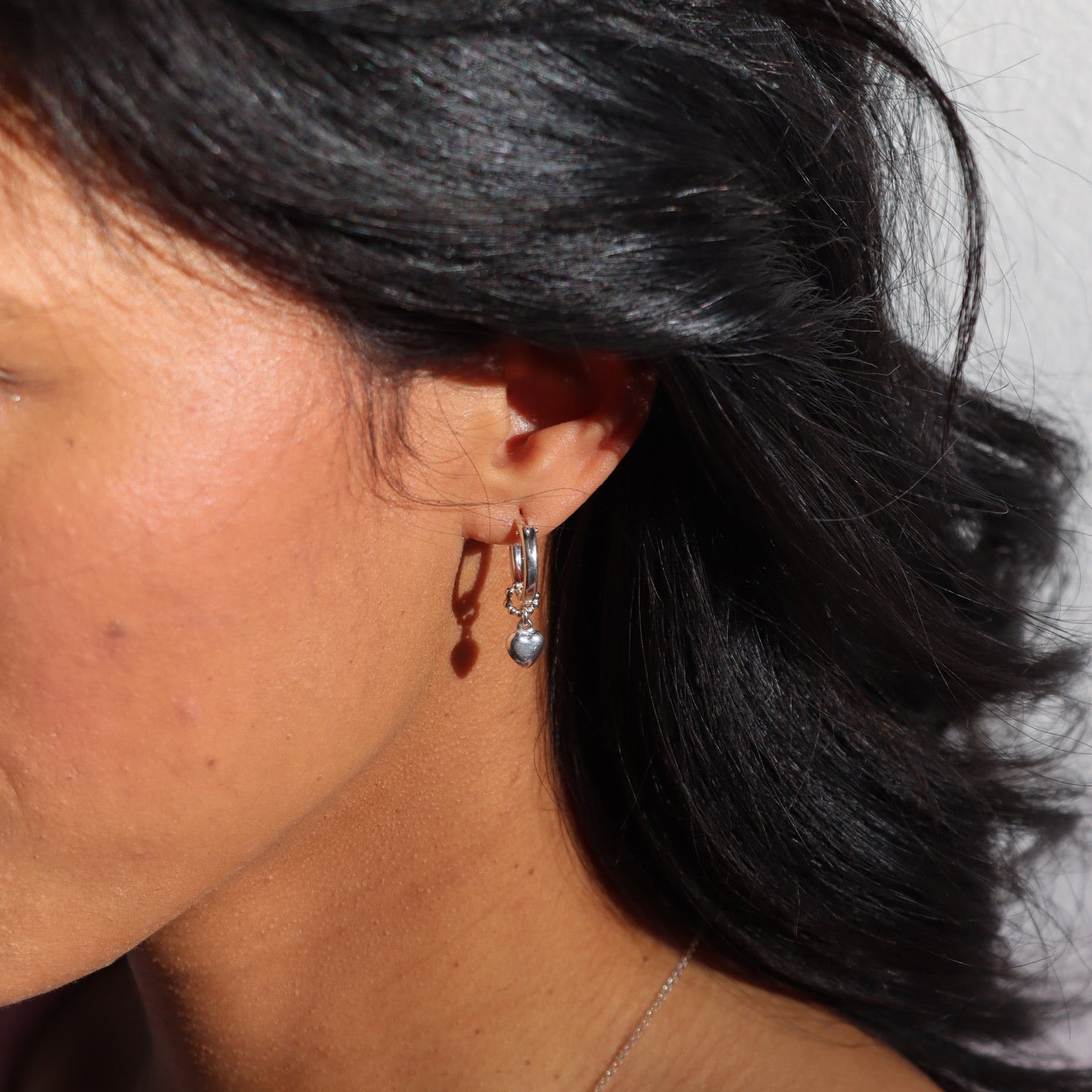 model wearing sterling silver heart charm on sterling silver classic hoops 