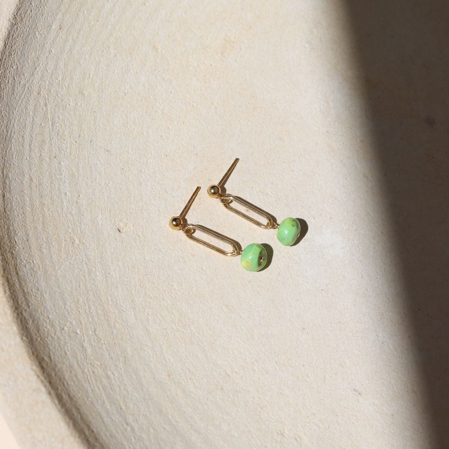 14k gold fill stud earrings with turquoise bead drops on a light dish