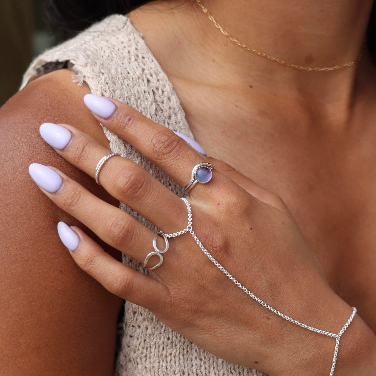 model wearing sterling silver hand chain with sterling silver rings and a sterling silver ring setting with a fluorite stone