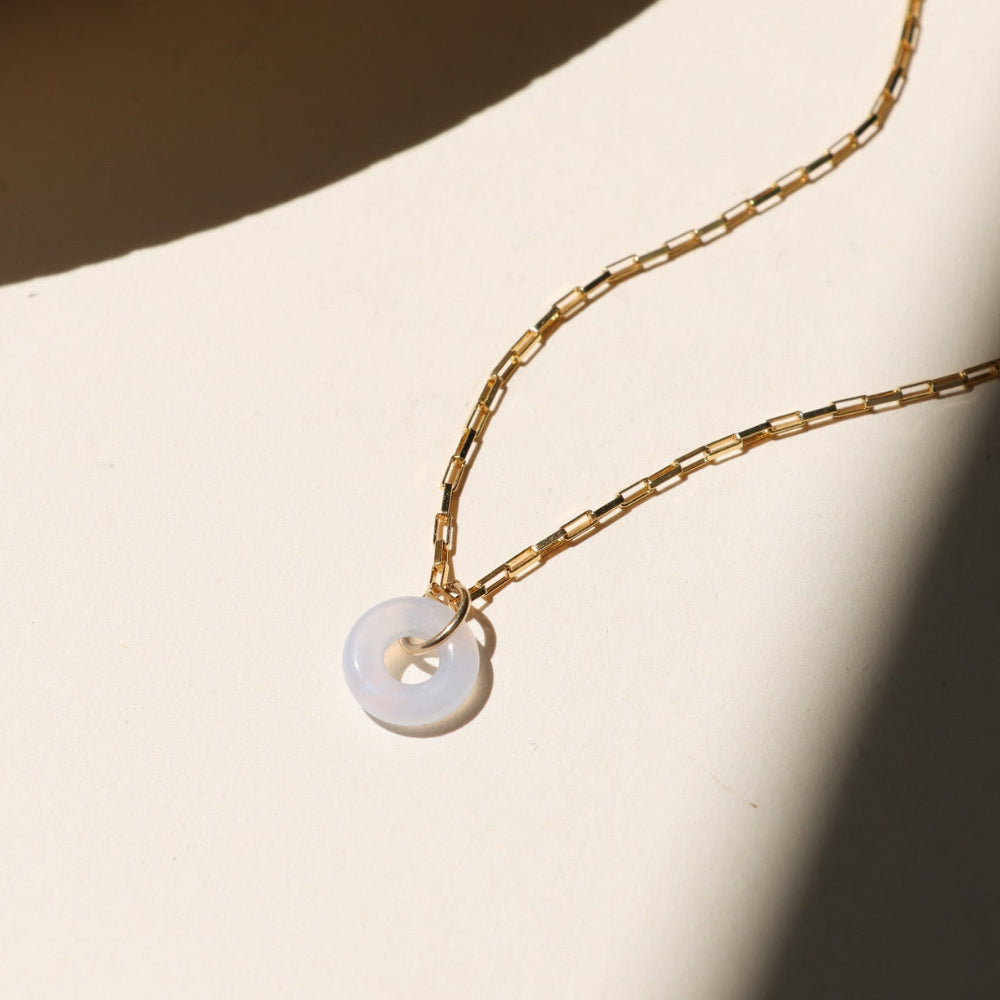 14k gold fill chain necklace with chalcedony donut pendant on a light surface