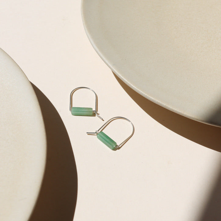 sterling silver arch shaped earrings with aventurine tube beads on a light surface
