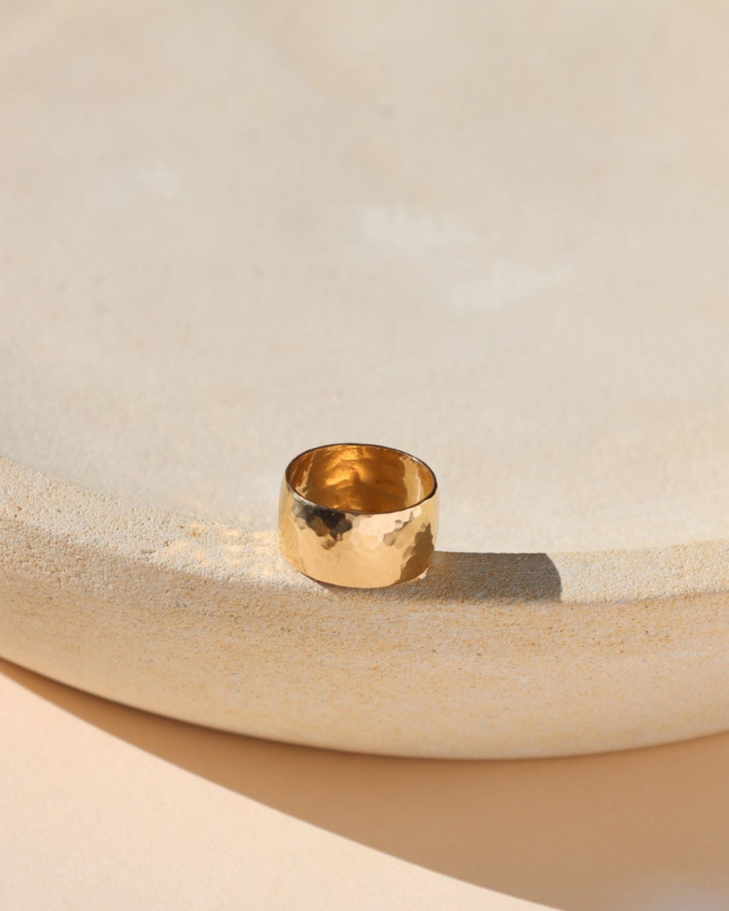 14k gold fill textured thick band ring on a light dish