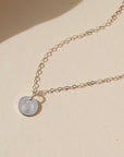 sterling silver disk with horseshoe stamp on a delicate chain necklace on a light dish