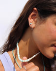 Model wearing a wave like sterling silver textured huggie earring. She pairs her hoop with a 4mm sterling silver turquoise stud. 