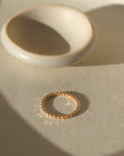 14k gold fill Sequin Ring placed on a white plate in the sunlight. This ring features our sequin band. This ring is perfect for stacking and everyday wear.