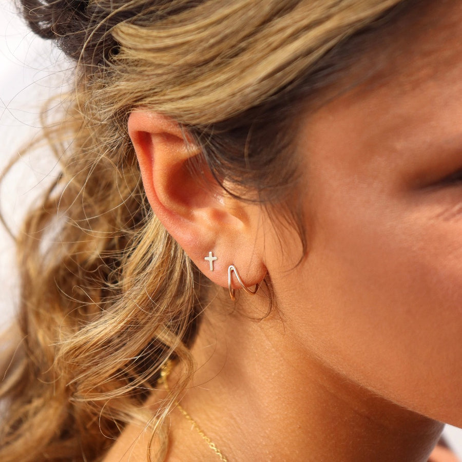 Model wearing 14k gold fill cross studs