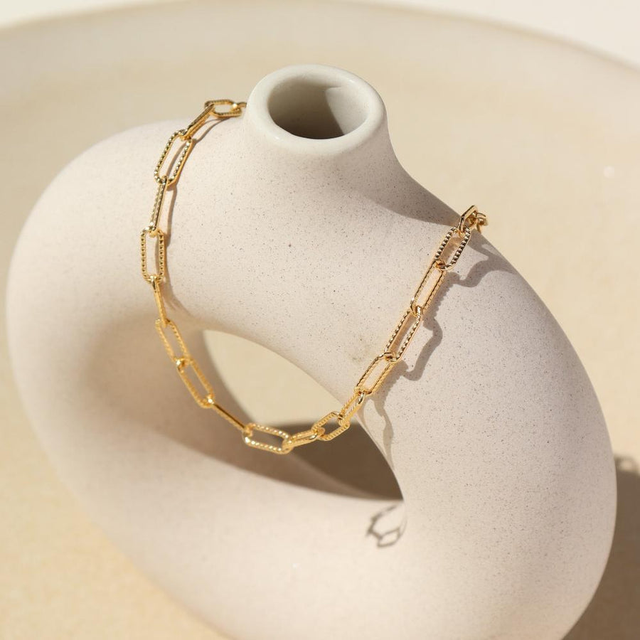 Gold filled piper anklet draped over stone dish