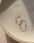 14k gold filled capsule hoops laid on a small plate