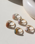 14k gold fill and sterling silver hand-set ocean jasper rings laid out on a cream colored backdrop in the sun