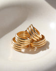 14k gold fill Trinity ring spirals into three bands, photographed on a white sunlit ceramic dish.This ring features the look of the three layered band look but its only one ring.
