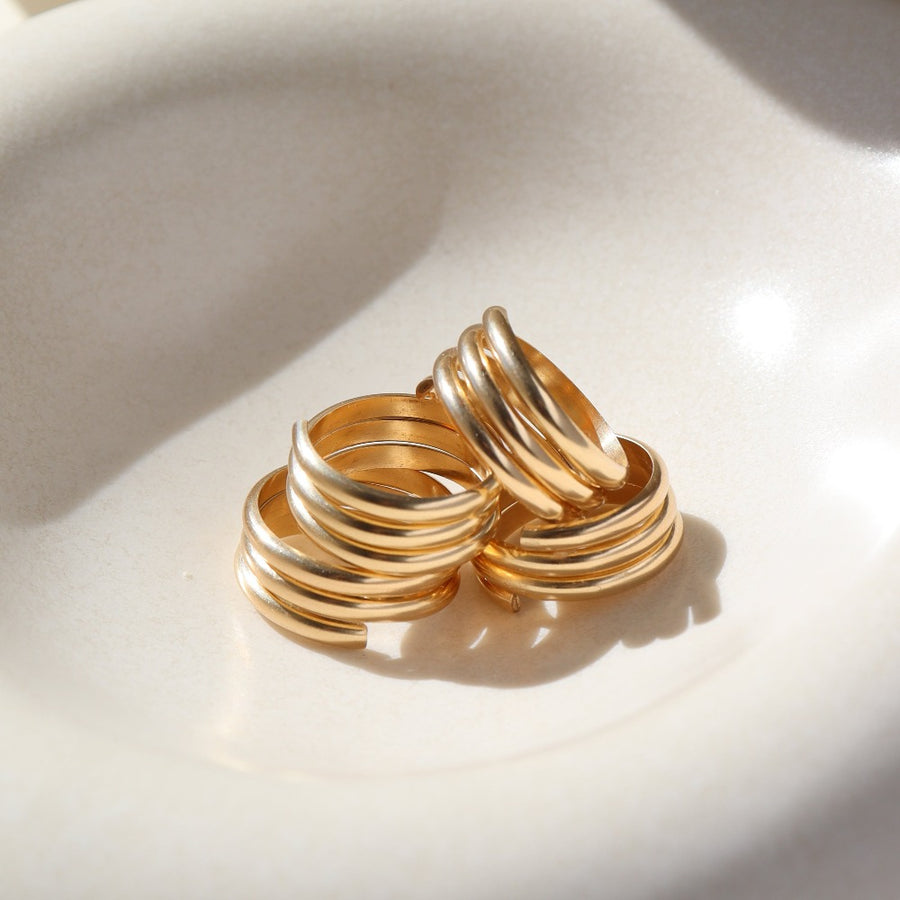 14k gold fill Trinity ring spirals into three bands, photographed on a white sunlit ceramic dish.This ring features the look of the three layered band look but its only one ring.