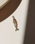 Large gold koi fish charms with red crystal eyes displayed on a neutral surface in warm natural light with shadowing.