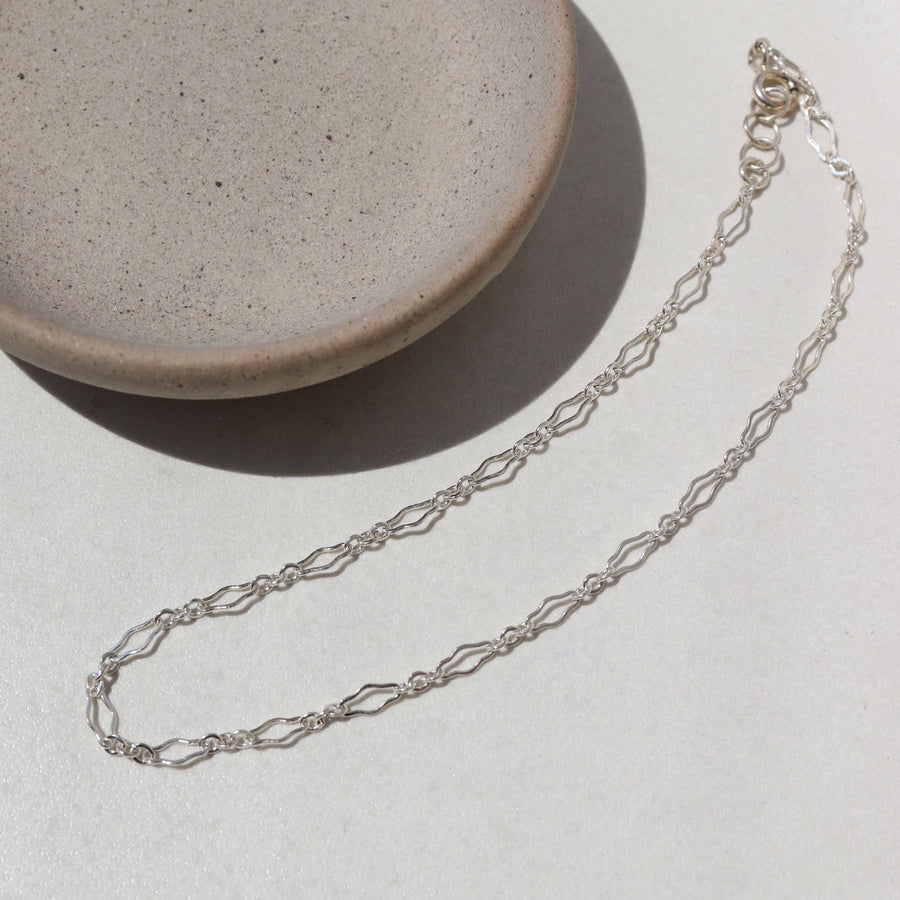 925 Sterling silver Clara Anklet laid on a white plate in the sunlight.