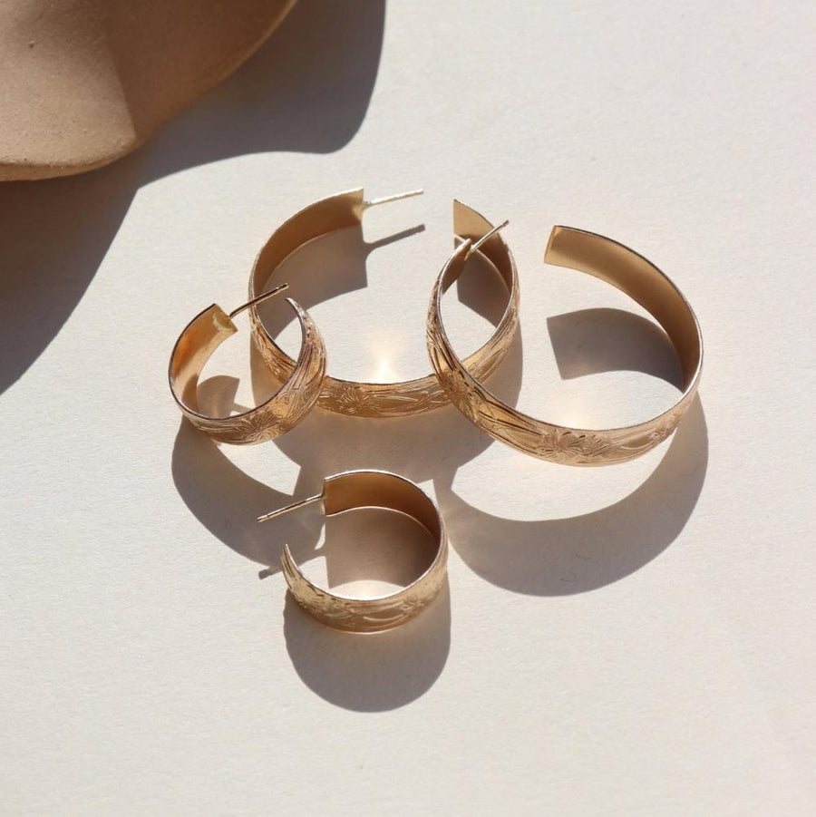 14k gold fill Florence hoops laid on a white plate in the sunlight