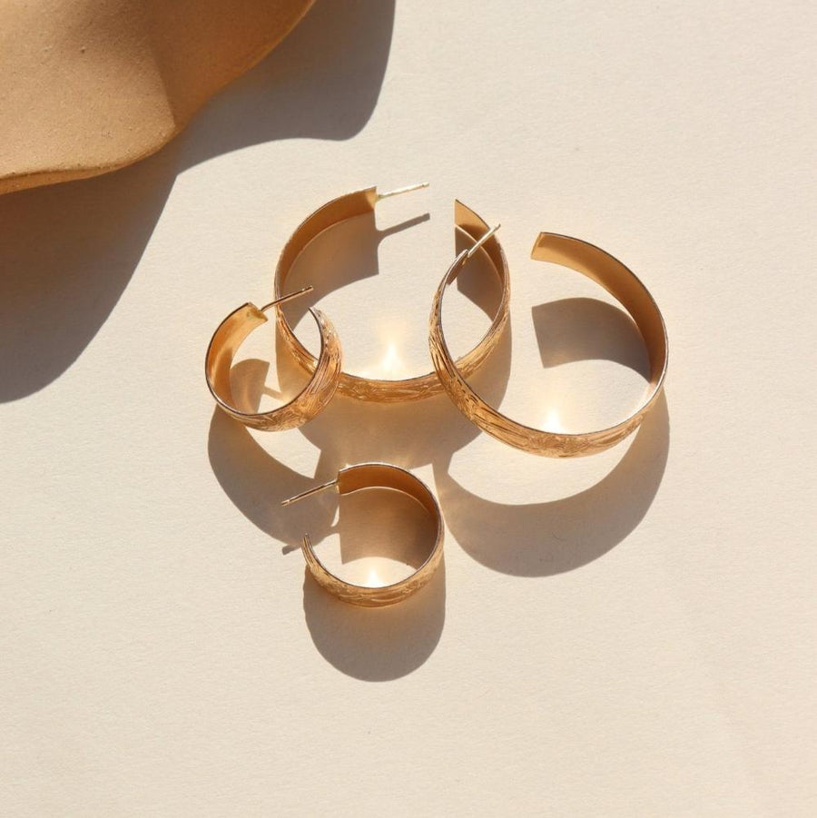 14k gold fill Florence hoops laid on a white plate in the sunlight